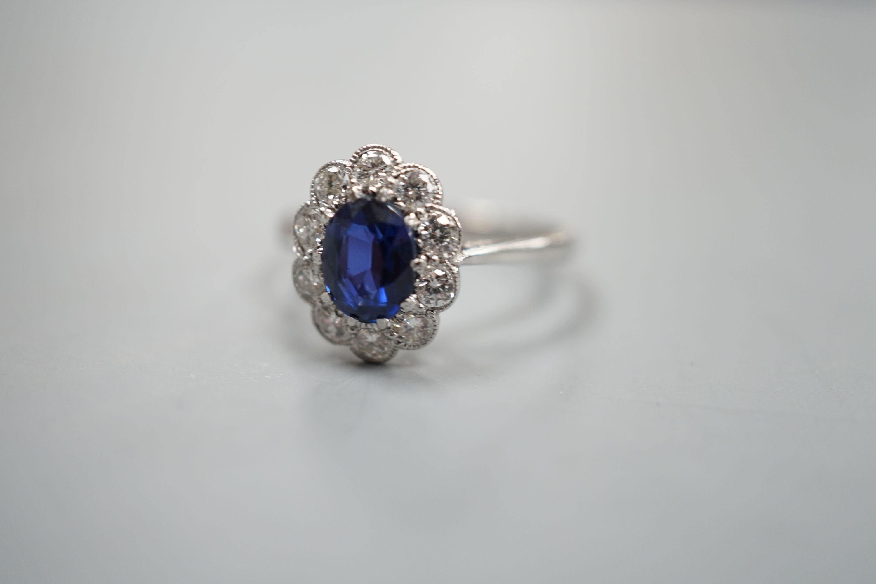 An 18ct and plat. sapphire and diamond set oval cluster ring, size N, gross weight 2.9 grams.
